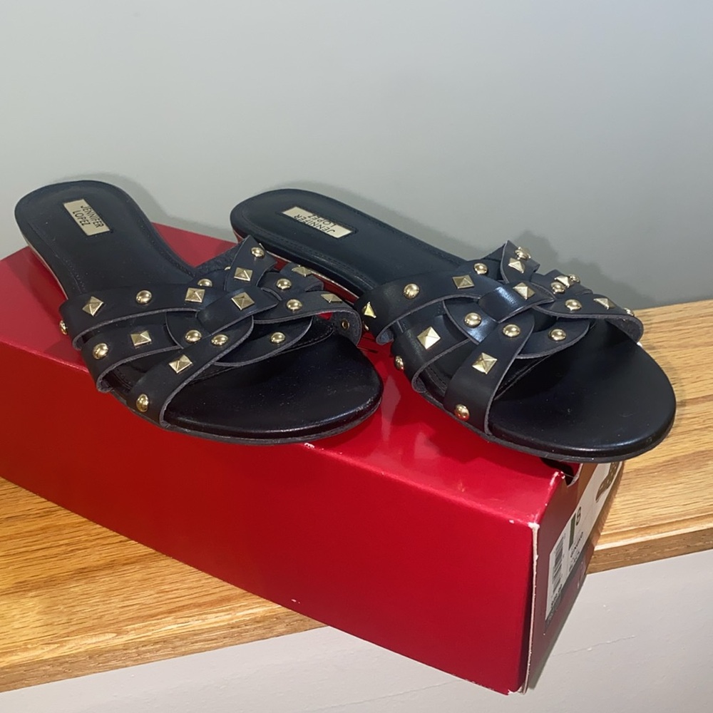 Black slip-on sandals with gold studded accents
